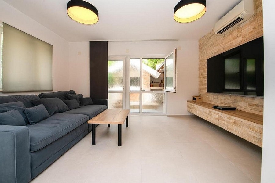 Moderná obývacia izba s pohovkou, TV stenou a vstupom na terasu