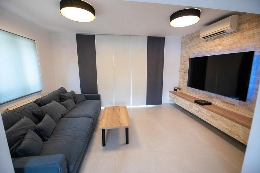 Obývacia izba s veľkým TV priestorom a moderným dizajnom stien
