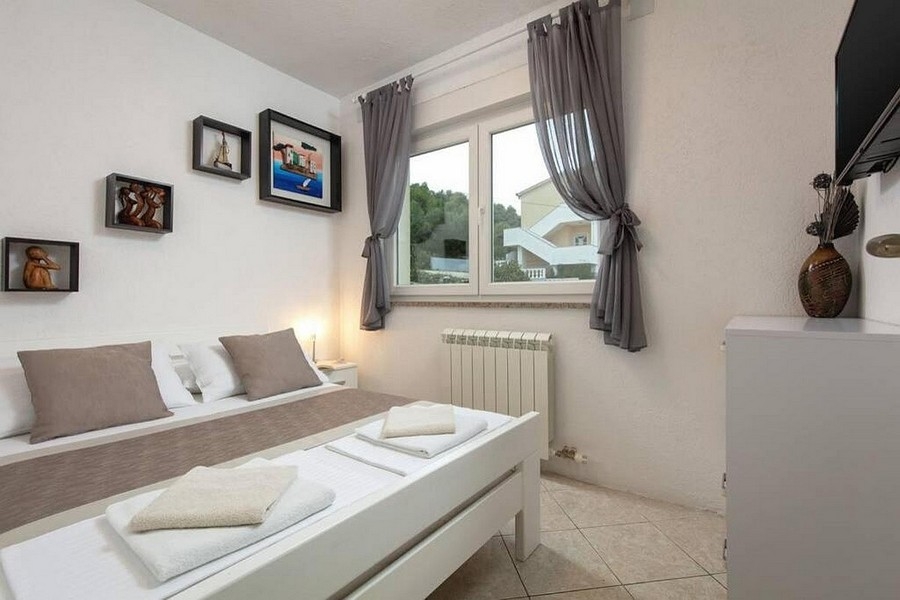 Spálňa s manželskou posteľou a oknom s výhľadom do zelene