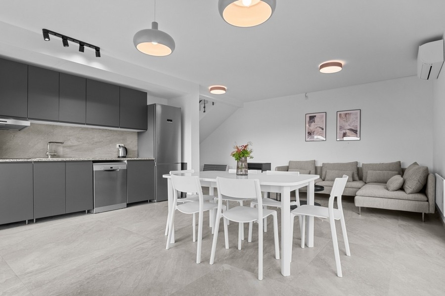 Svetlý obývací priestor s pohovkou a integrovanou kuchyňou v otvorenom pôdoryse