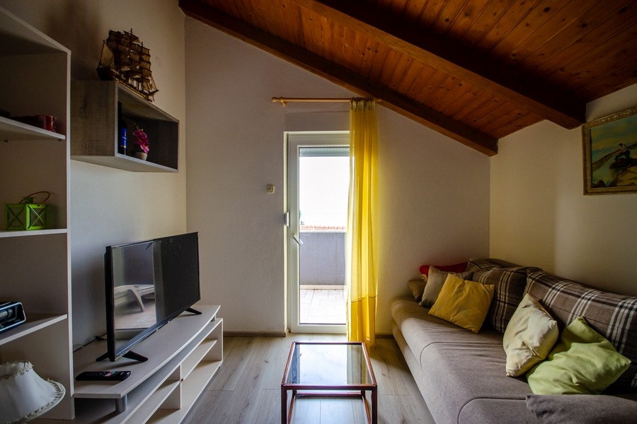 Obývacia izba v podkroví s pohovkou a vstupom na balkón