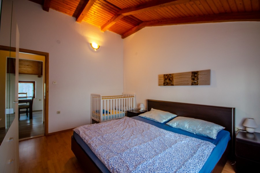 Spálňa s manželskou posteľou a trámovým stropom