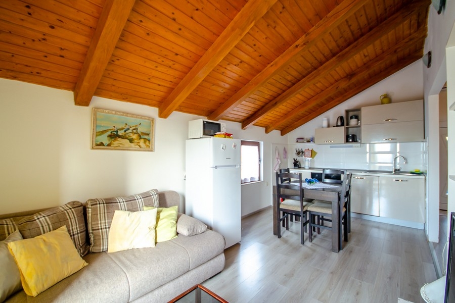 Obývacia izba a jedálenský kút s otvorenou kuchyňou a dreveným trámovým stropom