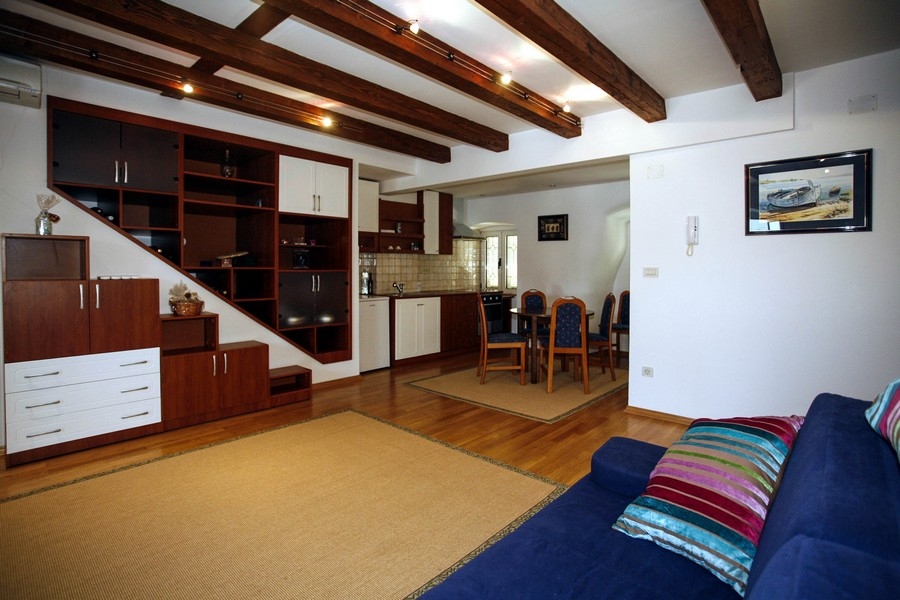 Obývacia izba s otvorenou kuchyňou a odhalenými drevenými trámami