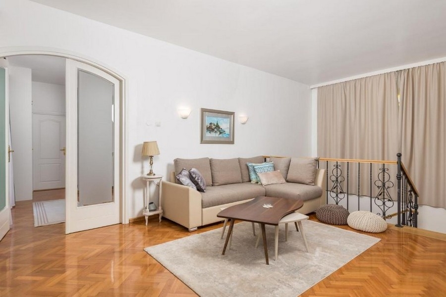 Obývacia časť na hornom poschodí s pohovkou a parketovou podlahou