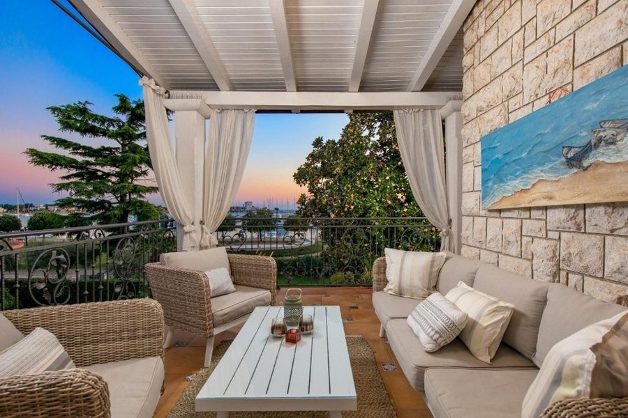 Balkón s obývacím nábytkom a výhľadom na more pri západe slnka