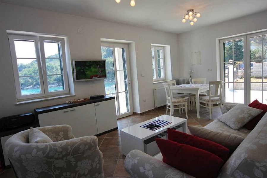 Svetlý obývací priestor s veľkými oknami a výhľadom na more