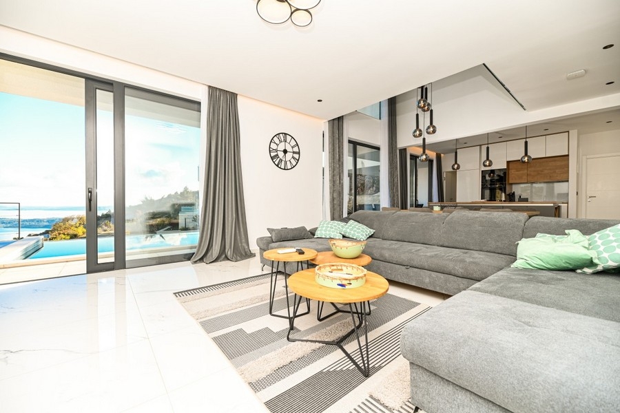Obývacia izba s veľkými oknami a výhľadom na bazén