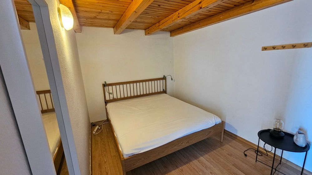 Spálňa s manželskou posteľou a trámovým stropom