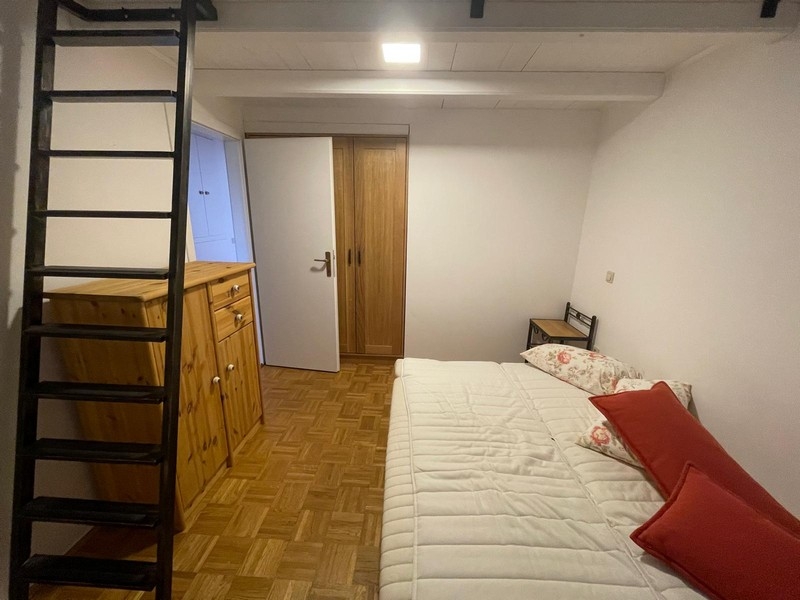 Spálňa s dreveným nábytkom a rebríkom na galériu
