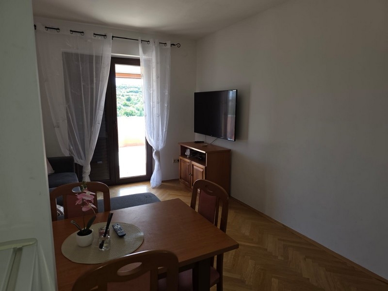 Obývacia izba so stolom, TV a dverami na terasu