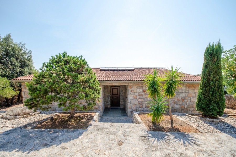 Vstup do kamennej vily s palmami a cyprusmi