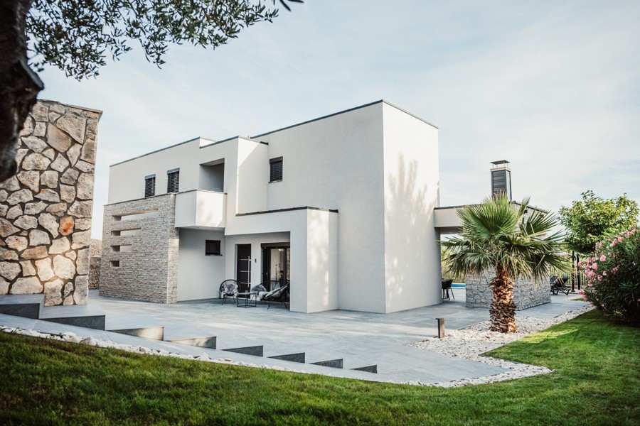 Moderná vila s trávnikom a kamennou fasádou