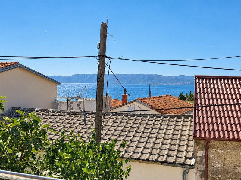 Výhľad nad strechami na more a ostrov Krk